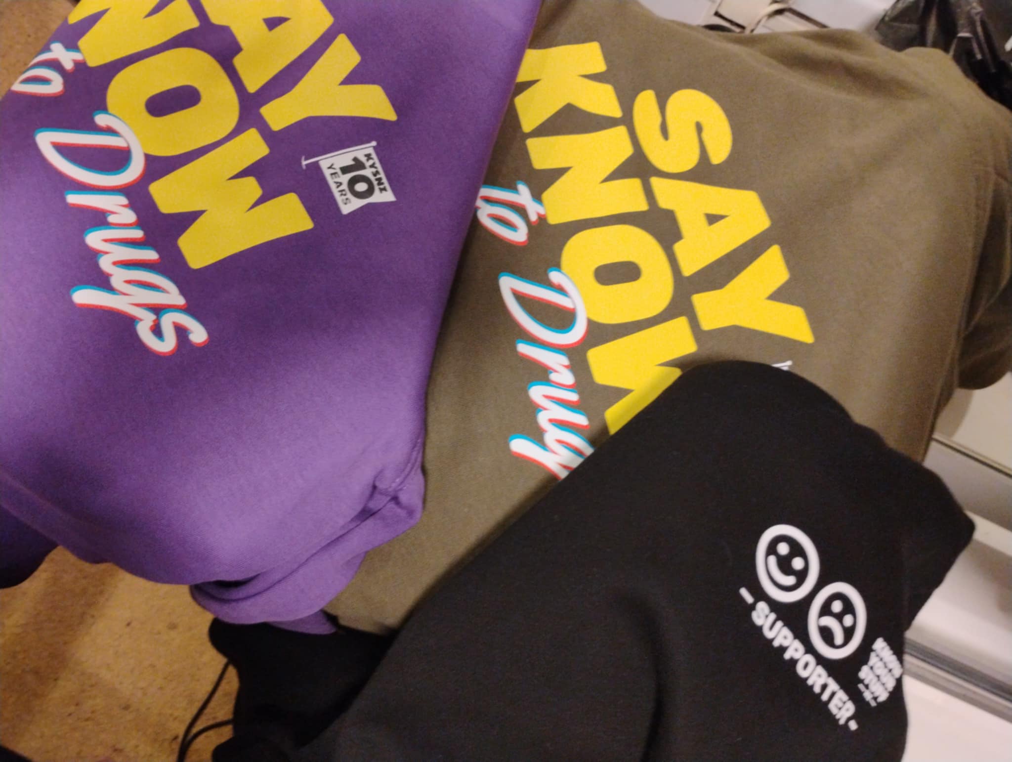 Two hoodies with 'Say No to Drugs' text on a surface.